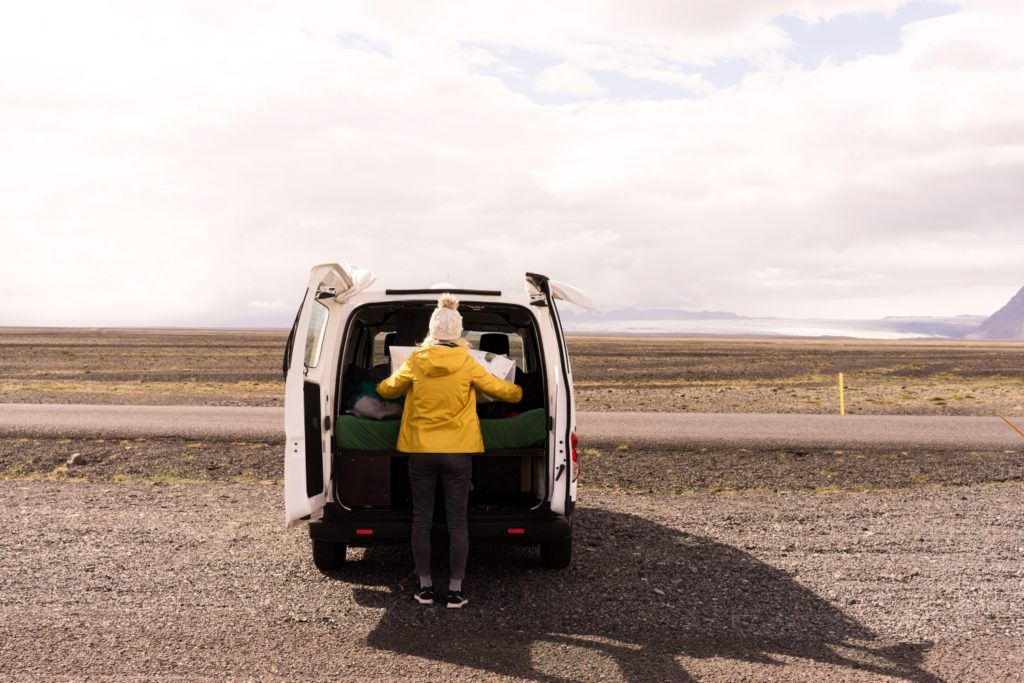 Woman looking at a map on the back of a camper van - Camping In Iceland