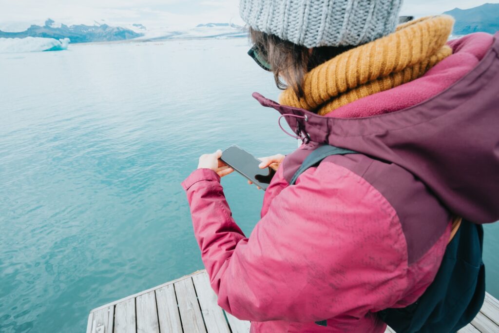 Young woman checking photos on smartphone at vatnajokull glacier